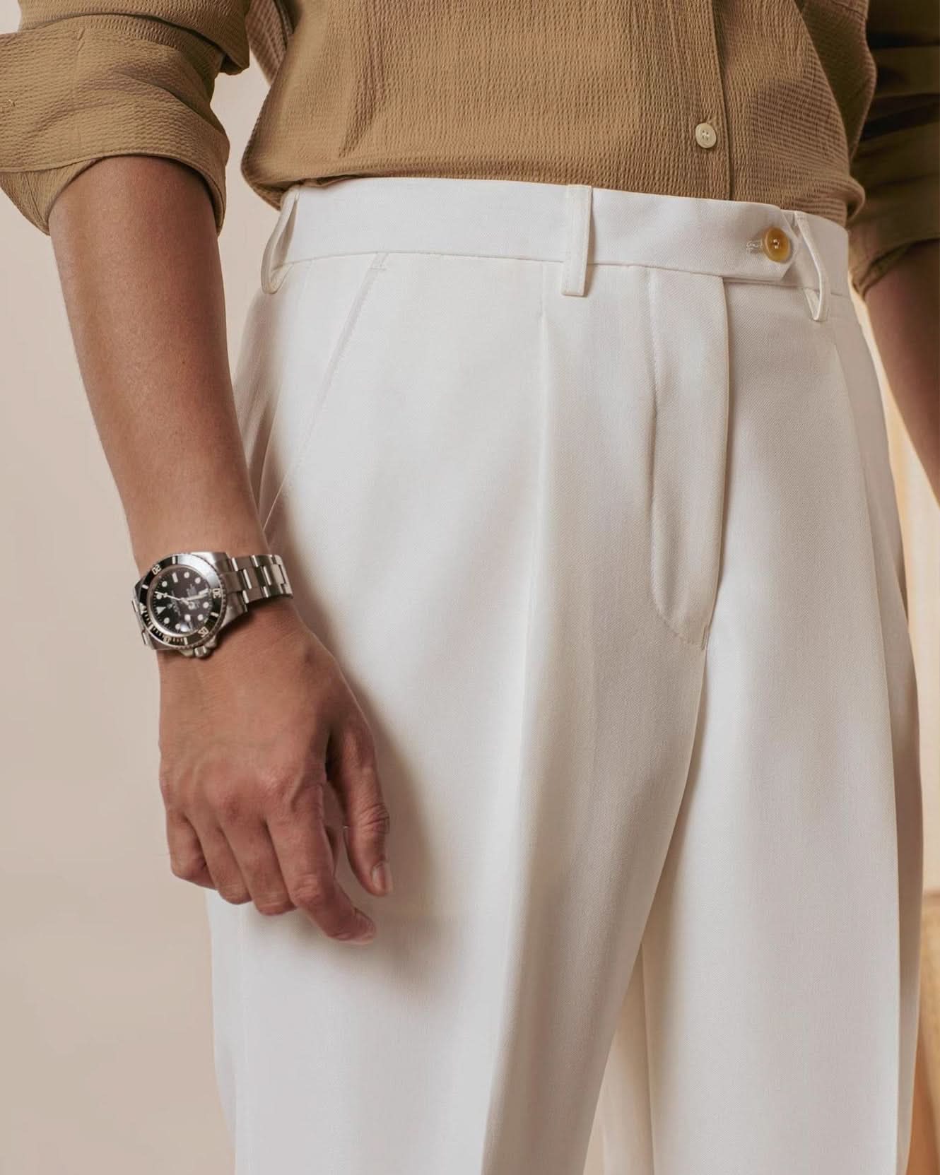 Wearing CjDropshipping’s Orta Tailored Trousers – Four Seasons Elegance, paired with a beige viscose-blend shirt and a silver wristwatch, this person’s look exudes casual elegance against a softly lit neutral background.