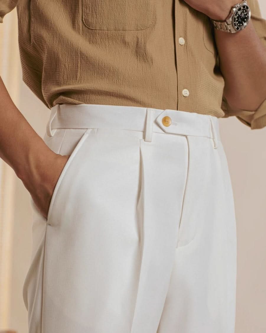 Wearing CjDropshippings Orta Tailored Trousers – Four Seasons Elegance, a person with a tan textured shirt tucked in, left hand in pocket and a silver watch on their right wrist exudes casual sophistication; only torso and upper legs are visible.